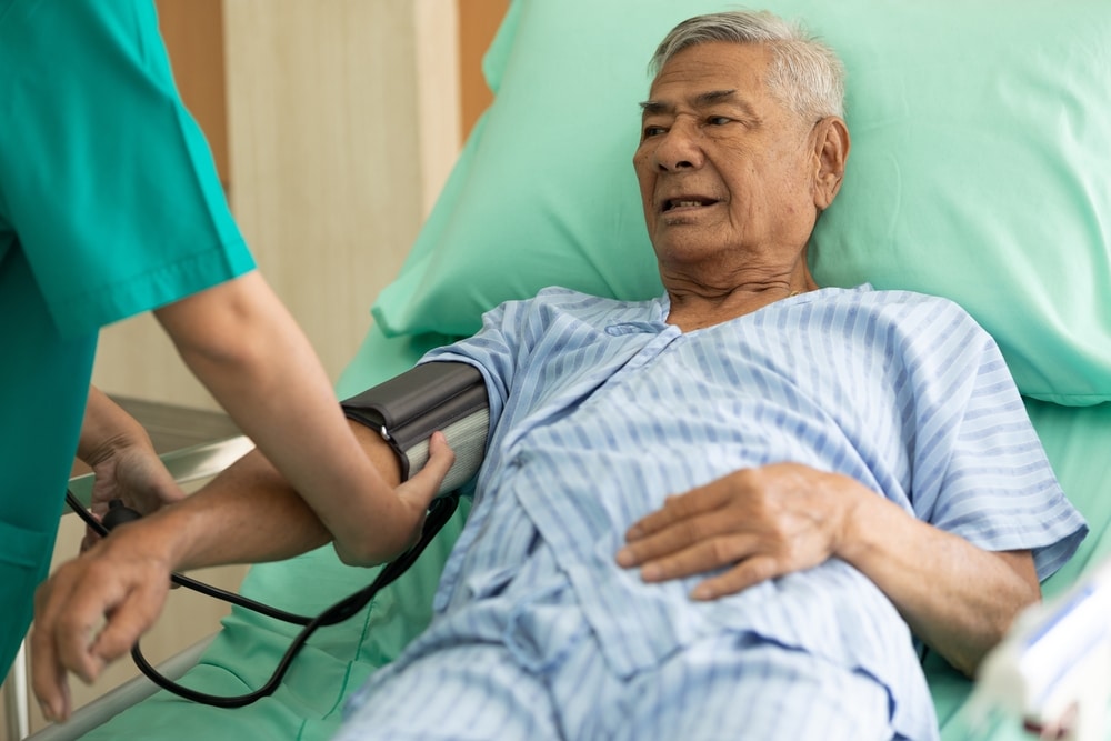 Senior,patient,lying,on,the,bed,and,nurse,measuring,blood