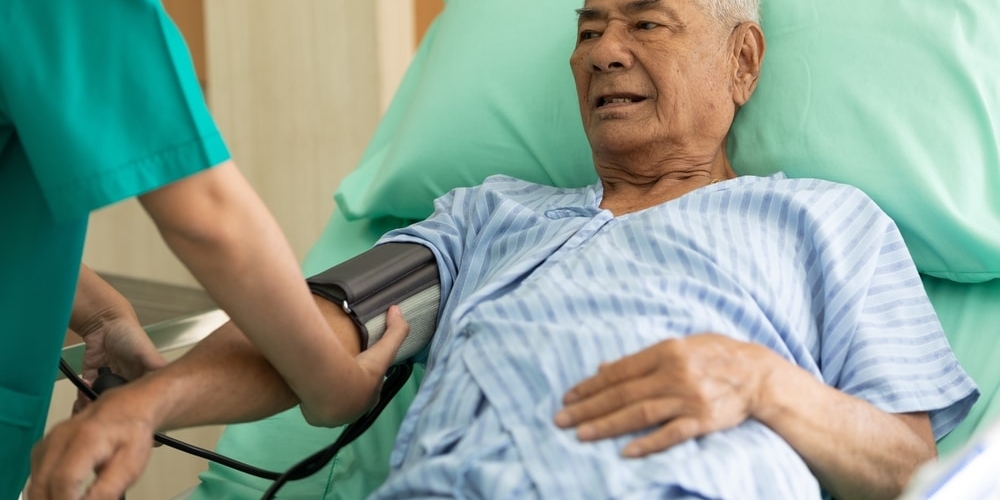 Senior,patient,lying,on,the,bed,and,nurse,measuring,blood