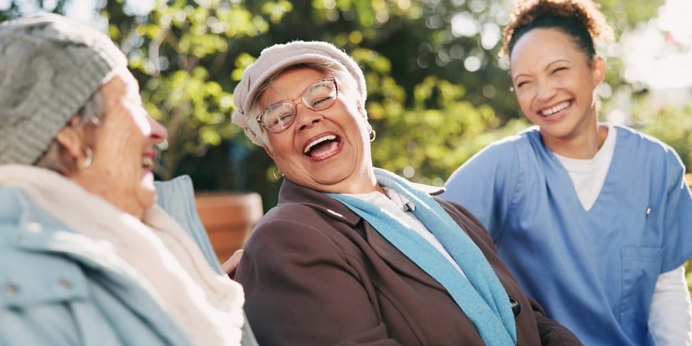 Young Nurse Laughing With Elderly Women Outdoors